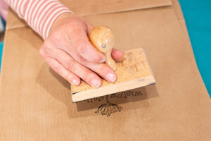Staff member pressing stamp of wistow galleries logo onto the kraft bag.