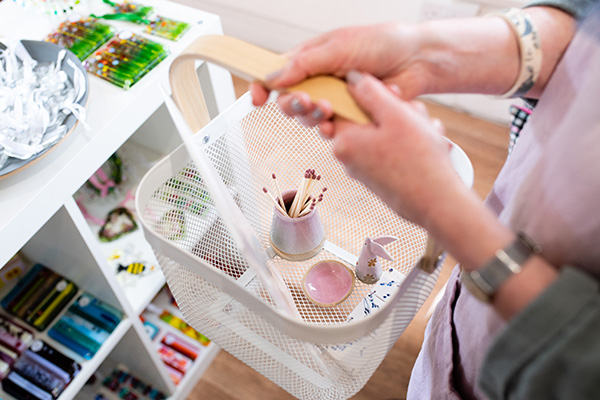 Person shopping holding a basked with multiple handmade gifts in it.
