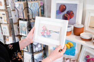 Picture of a staff member holding a floral print in their hand in a white frame.