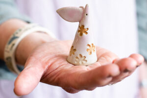 Person golding a handmade decorate mouse ornament with ears and floral imprints that have been painted.