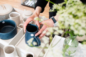 Picture of handmade blue and white ceramics with a person holding a blue jug.