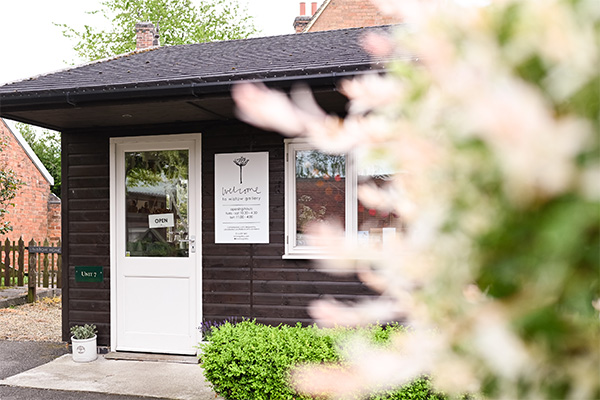 Outside picture of the entrance to wistow gallery with a floral plant blurred for effect.