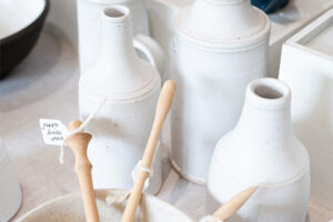 Multiple hand made white vases / jugs with some speckles on them.